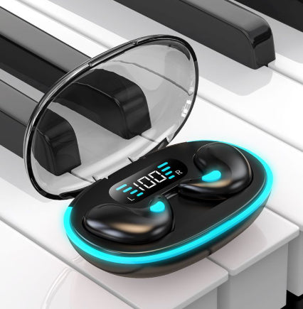 Black sleep earbuds glowing soft blue in an open charging case resting on piano keys